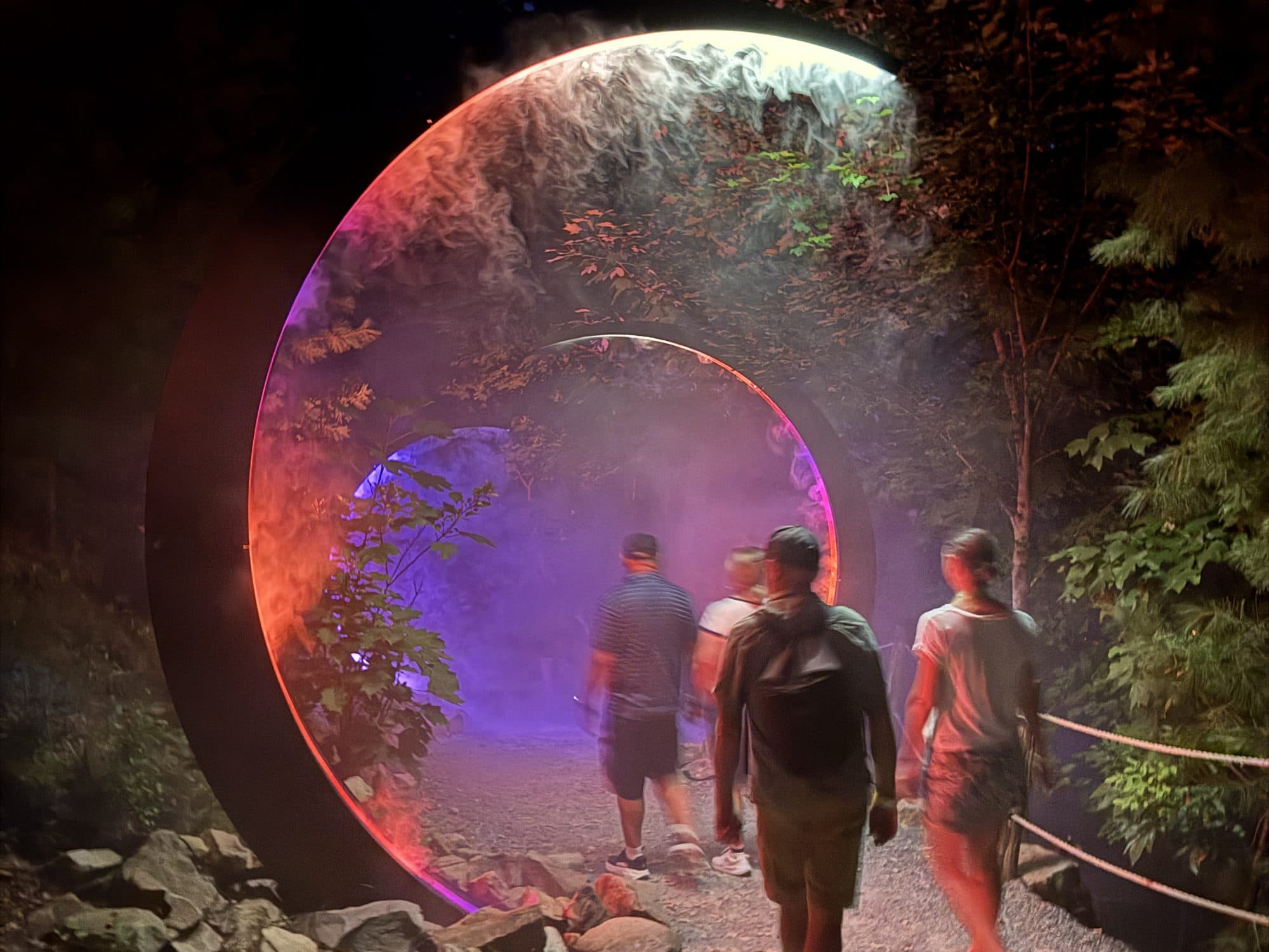 Campers walking through a glowing ring of light and mist on Anakeesta's Astra Lumina night walk