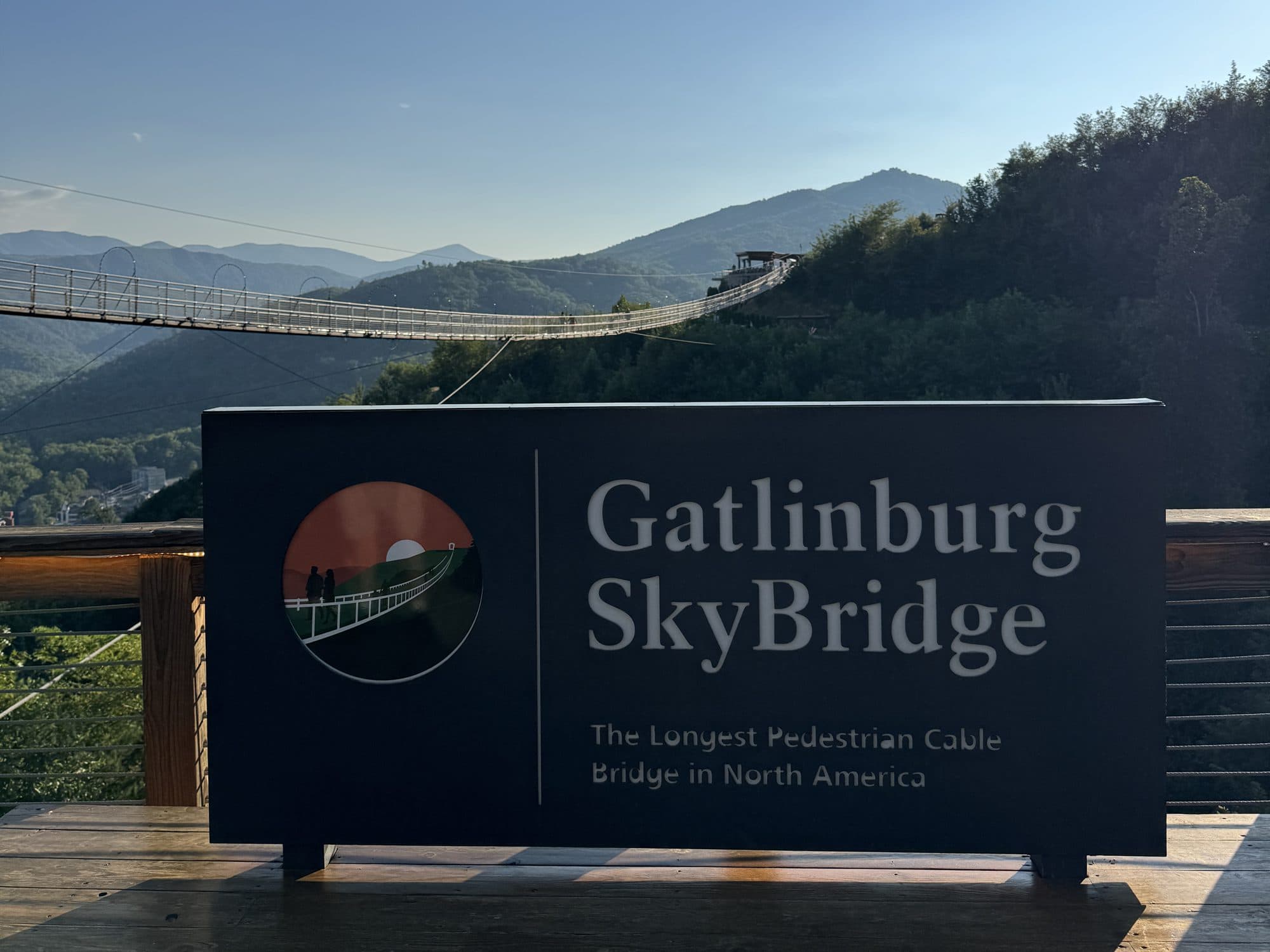 The Gatlinburg SkyBridge sign at SkyPark, with the bridge stretching across the valley behind it