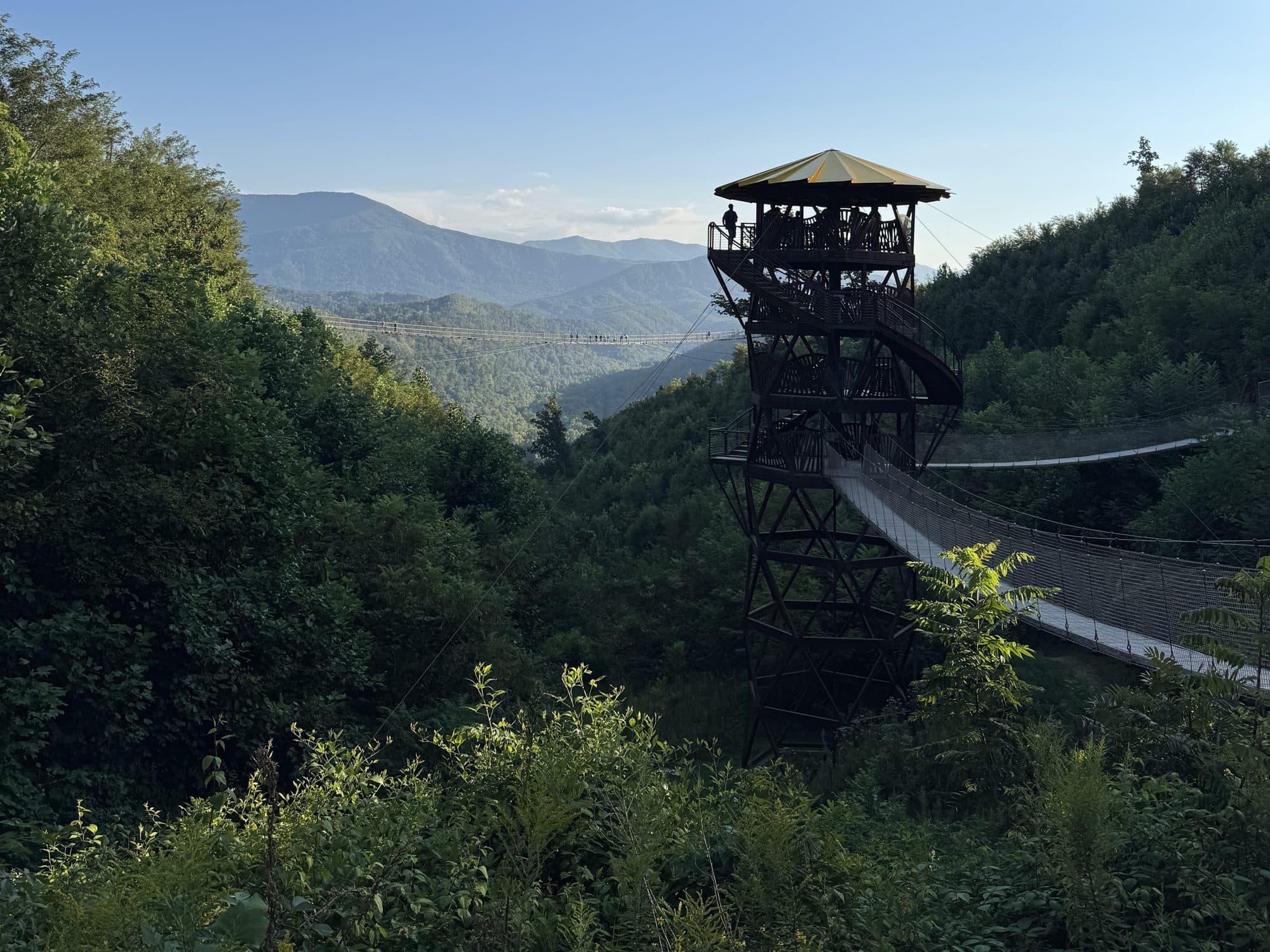 The Tulip Tower and suspension bridge at Gatlinburg SkyPark in evening light, with the Smokies behind