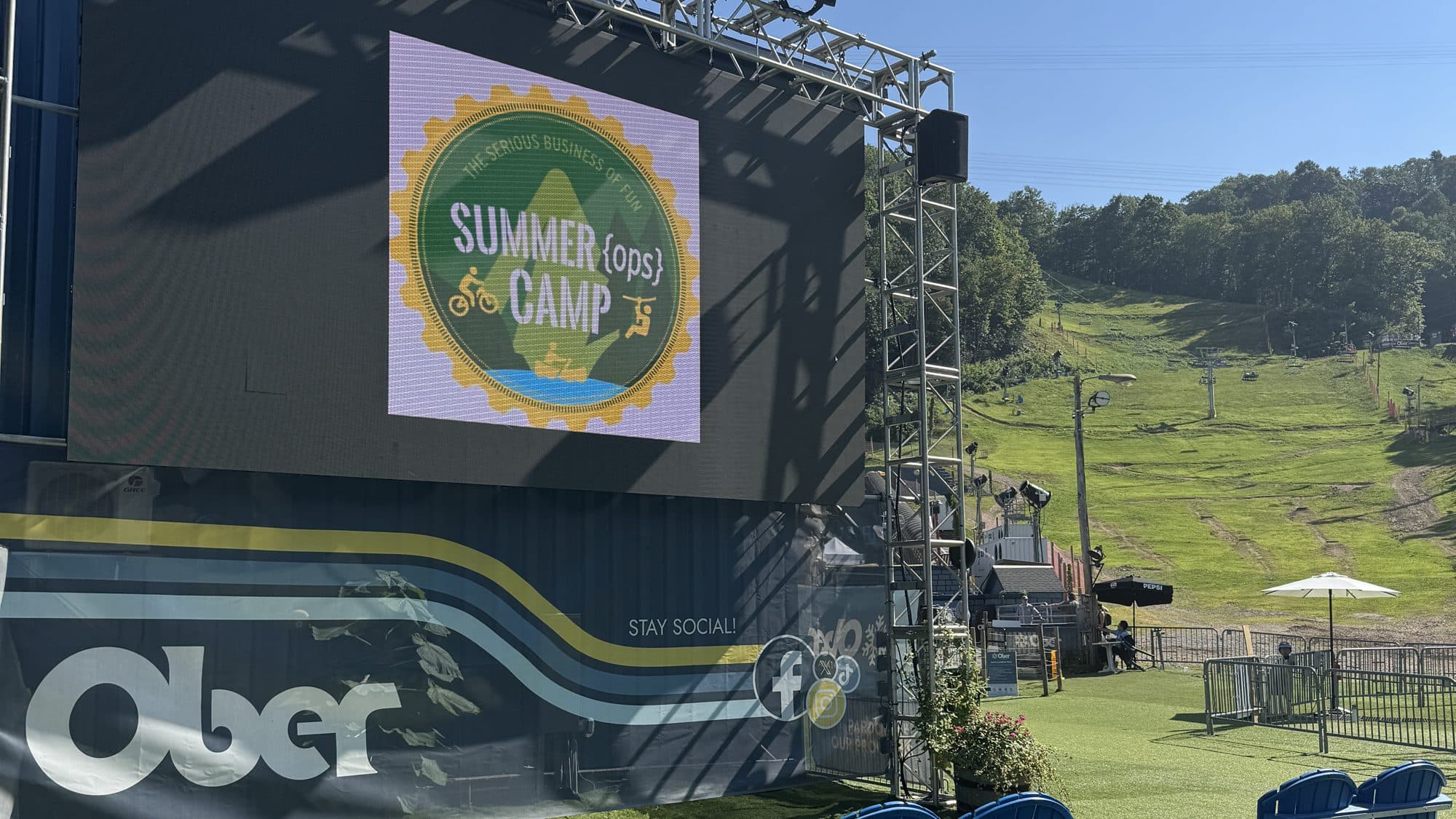The Summer Ops Camp logo on the big screen at Ober Gatlinburg, with the summer slopes behind